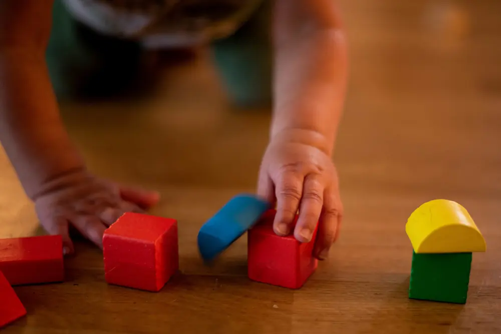 Toddler exploring building blocks with gentle guidance
